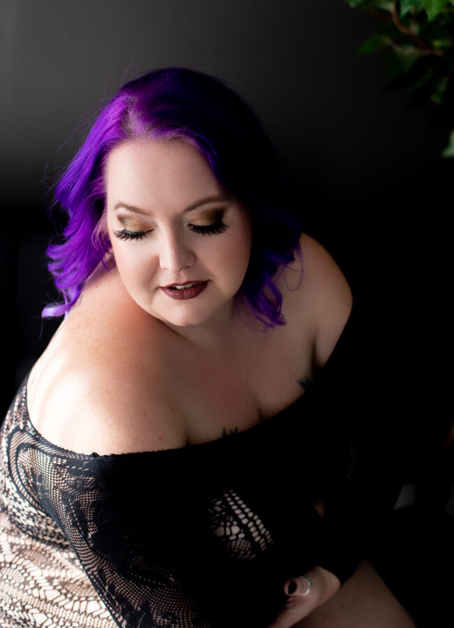 Purple haired queen poses for a boudoir session