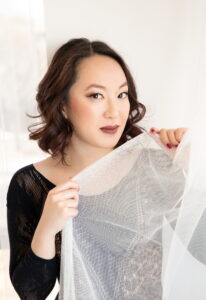 Woman with brown hair holding tulle up to her face