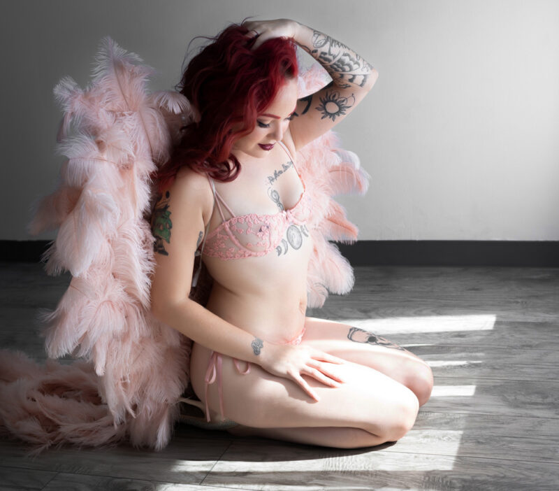 red-head poses in pink with pink angel wings