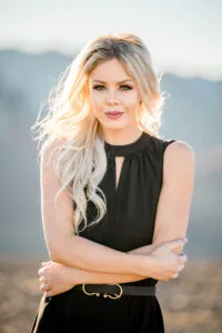 Blonde woman stands outside in the mountains